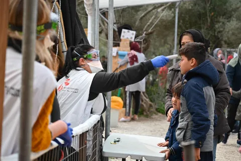 Medicinsk personal tar temperaturen på ett barn i flyktinglägret Moria, på den grekiska ön Lesbos.