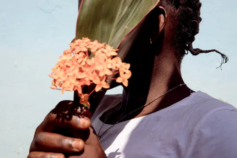 En kvinna i Centralafrikanska republiken håller en blomma framför sitt ansikte.