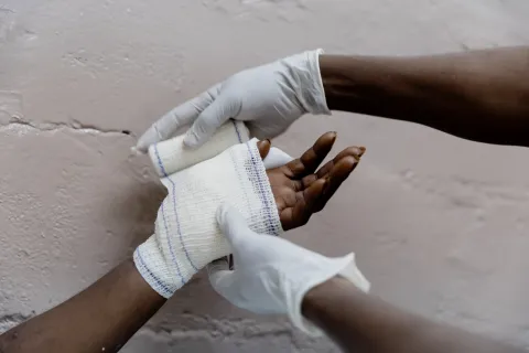 Två händer syns, en hand får bandage.