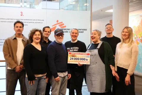 En grupp glada personer håller i en check där det står 24 miljoner